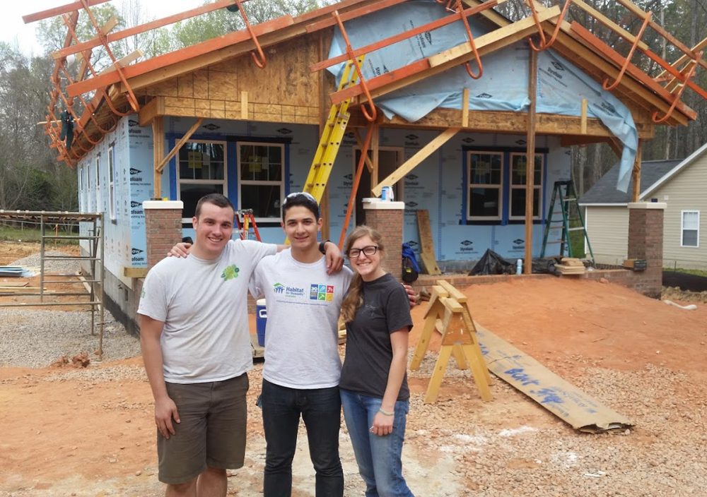 Leadership Academy students pose in front of a Habitat for Humanity house they're helping to build