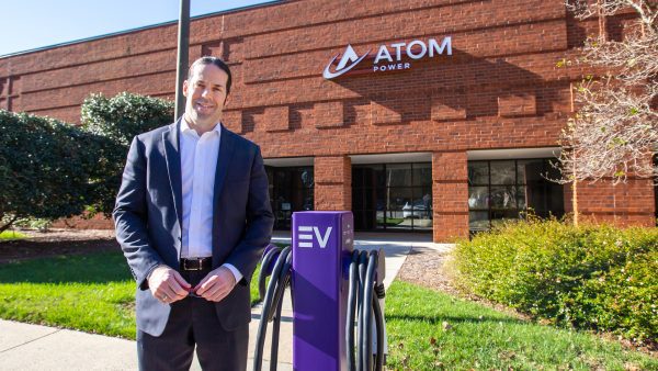 Image shows Charlotte Engineering alumnus Ryan Kennedy standing outside the offices of Atom Power