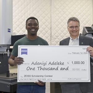 Adeniyi Adeleke holds check with Ed Morse, Director of the Center for Precision Metrology