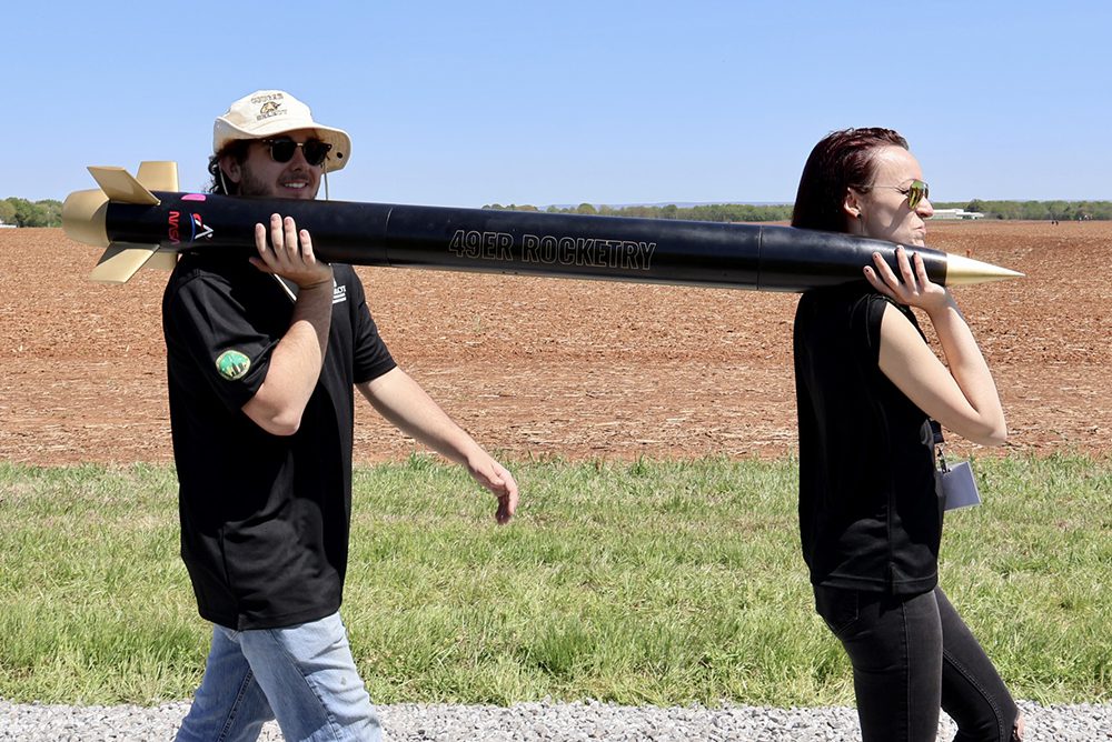 Two members of 49er Rocketry team carrying the team's rocket