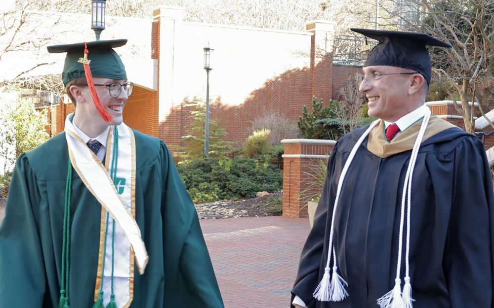 Scott Stewart Jr. and his father taking a walk while wearing their cap and gowns