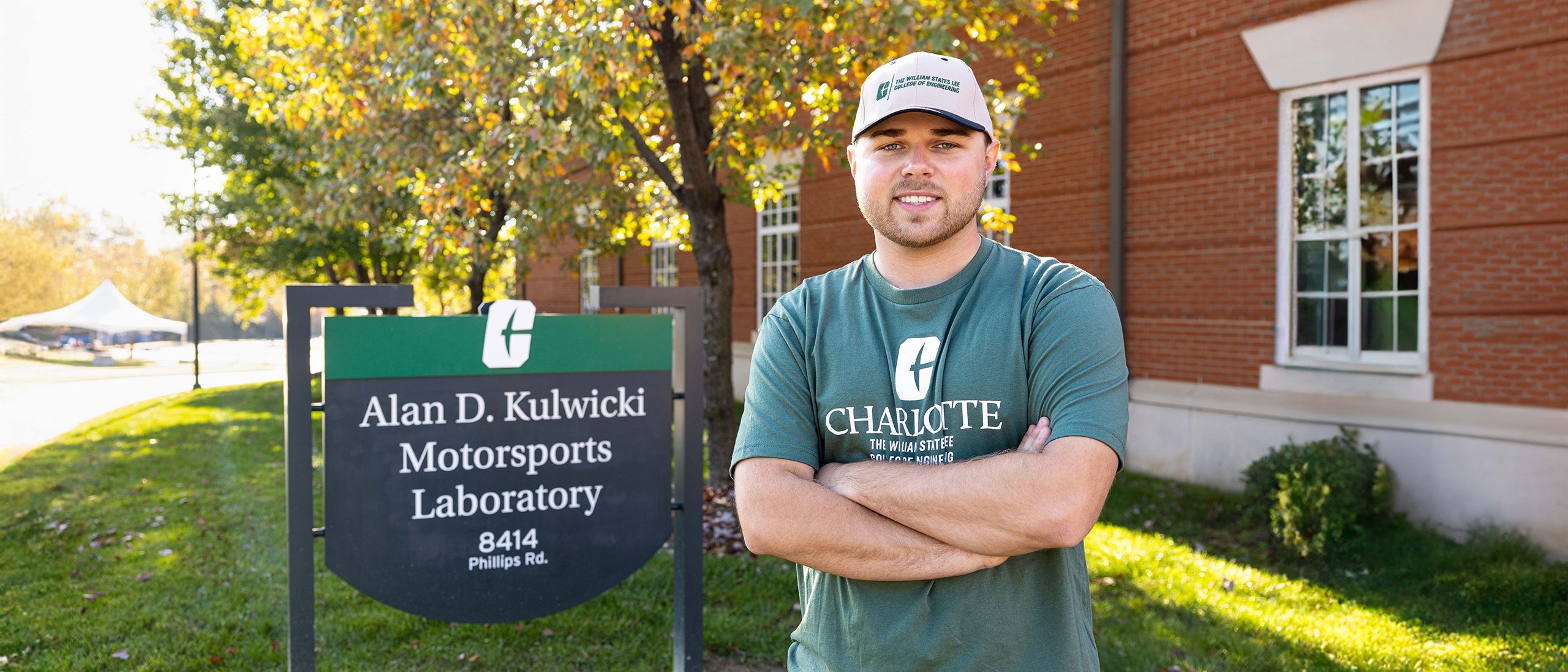 Layne Riggs standing beside the sign for the Kulwicki Motorsports Lab