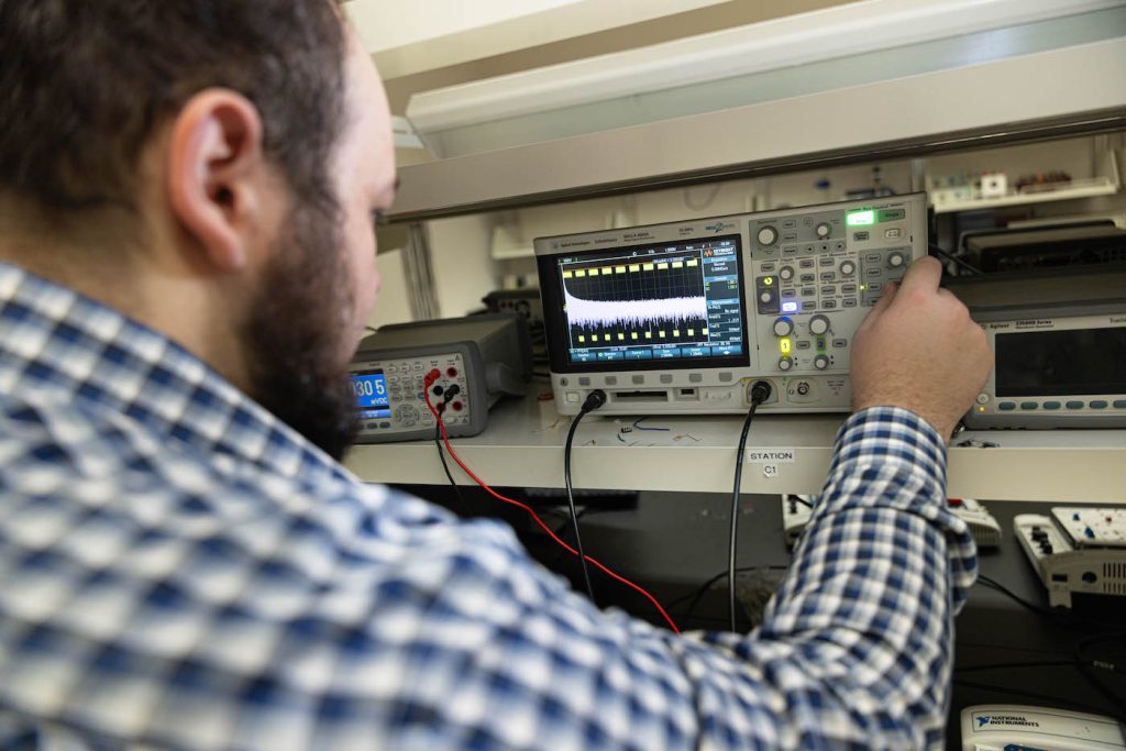 Electrical engineering graduate student works with instrument in a lab
