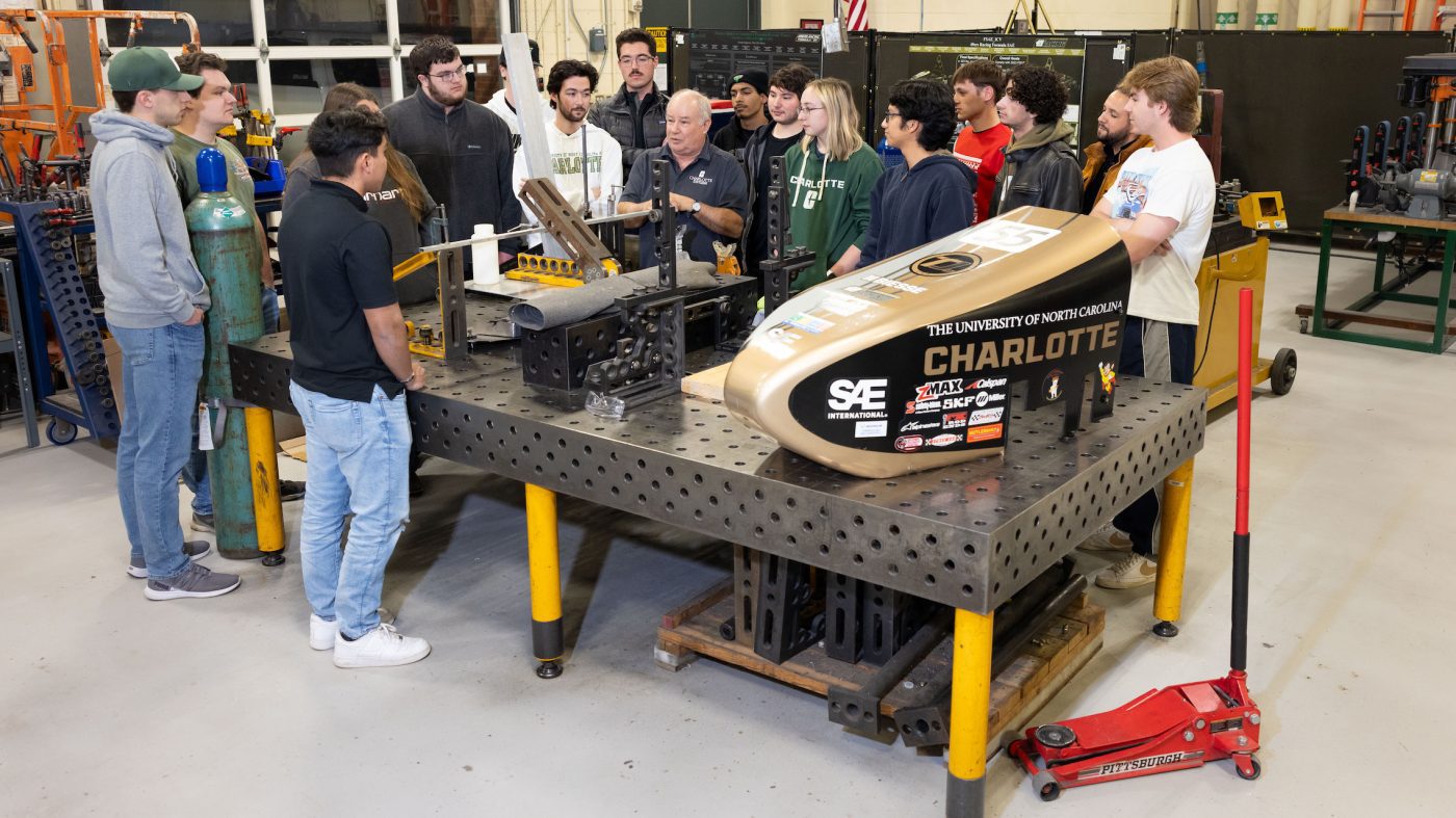 Jim Fox speaks to a group of students gathered around a table in the Kulwicki Motorsports Laboratory.