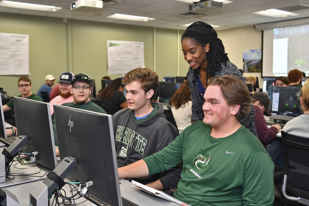 Professor speaks with students sitting at computers