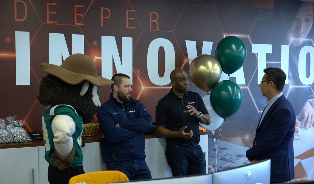 People standing and talking to each other with innovation wall behind them