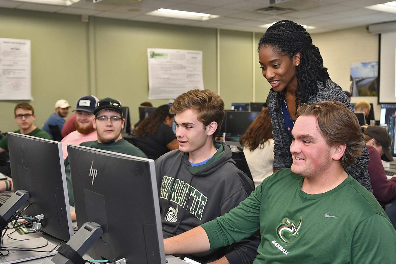 Professor speaks with students sitting at computers