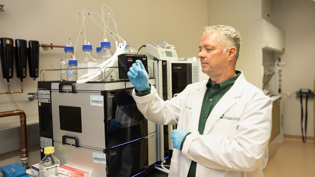 Roger Tipton holds vial in laboratory