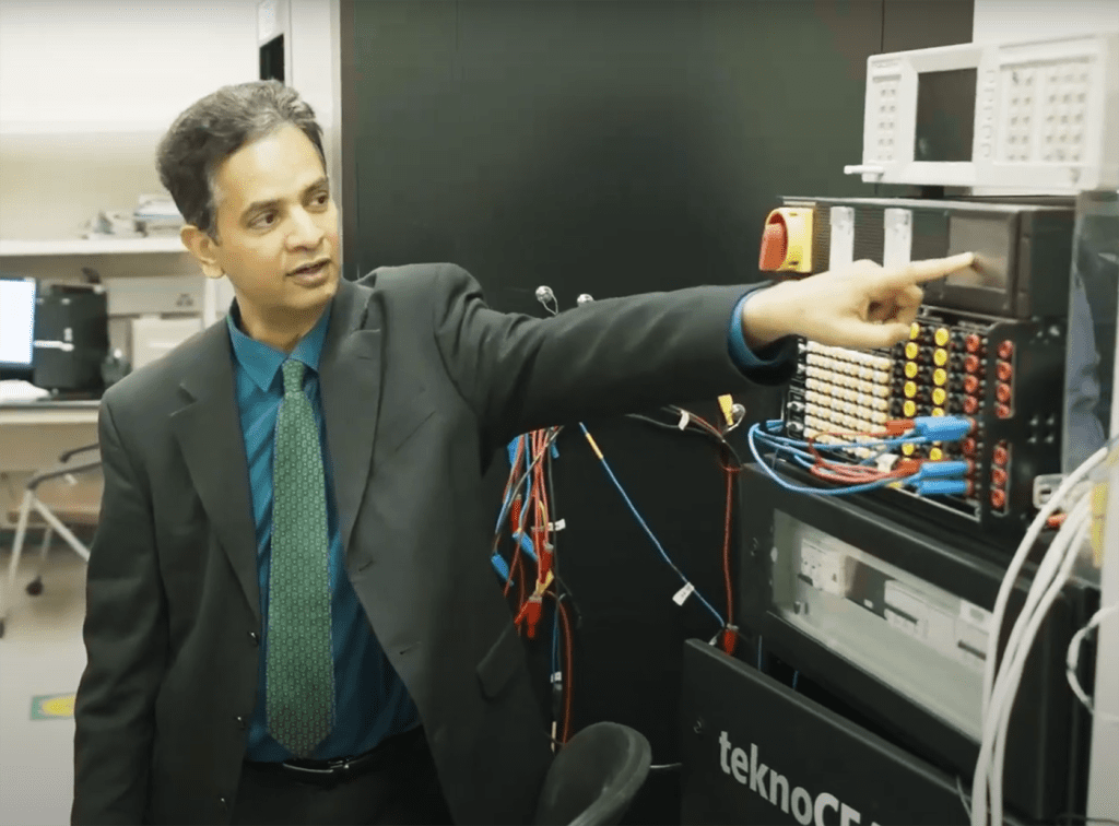 Sukumar Kamalasadan pointing to screen on instrument in lab