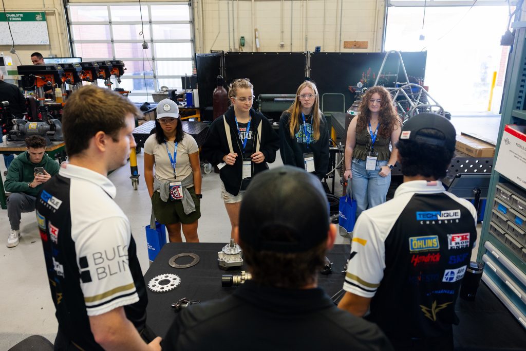 Niner Engineering students show automotive parts to high school students for Manufacturing Day