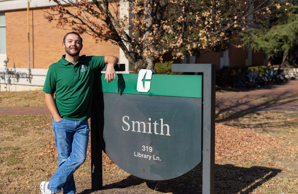 Engineering student Nick Dietterick stands beside sign for Smith Building