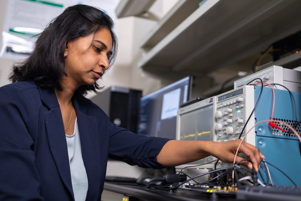 Student sits at desk with computer and electrical wires and equipment