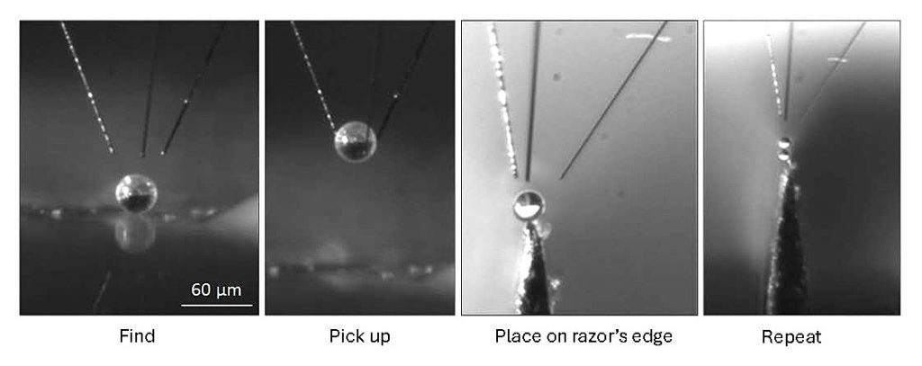 High magnification CCD image showing a three finger hand picking up a microsphere and placing it on the edge of a razor blade.