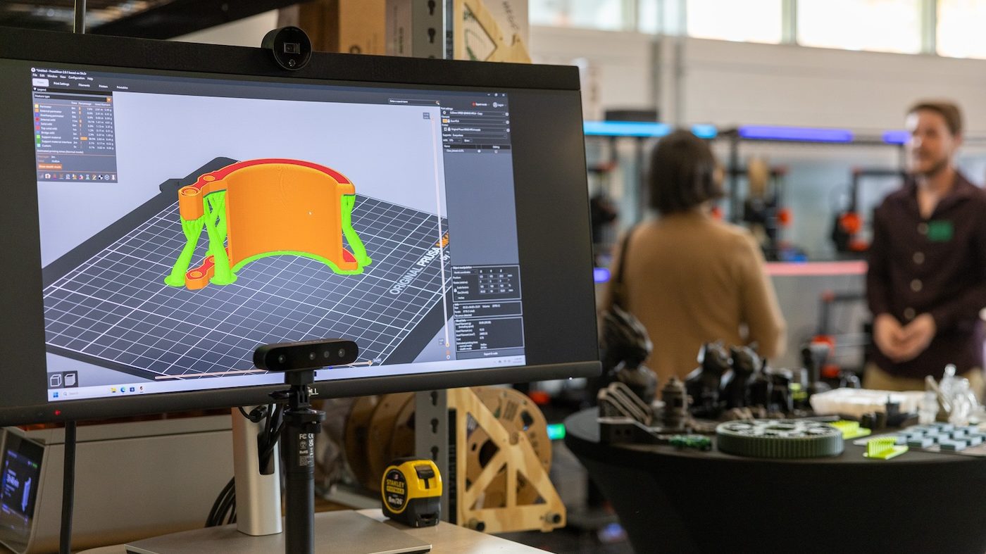 Close up of computer monitor with two people talking in the background
