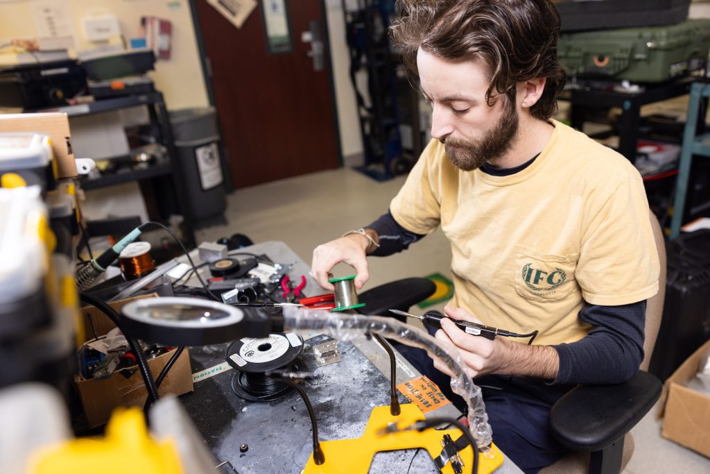 Male student sit at soldering station in a lab.