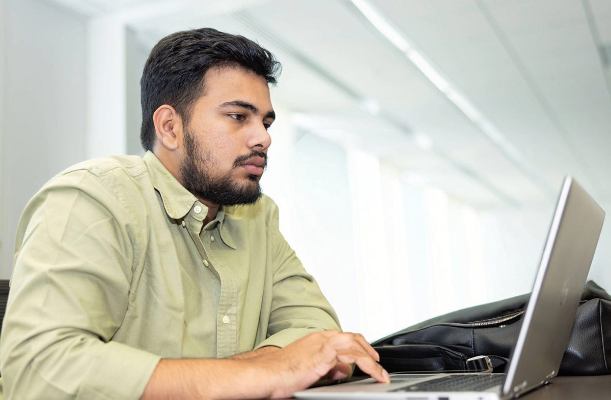 Male student working at a desk with a laptop on it
