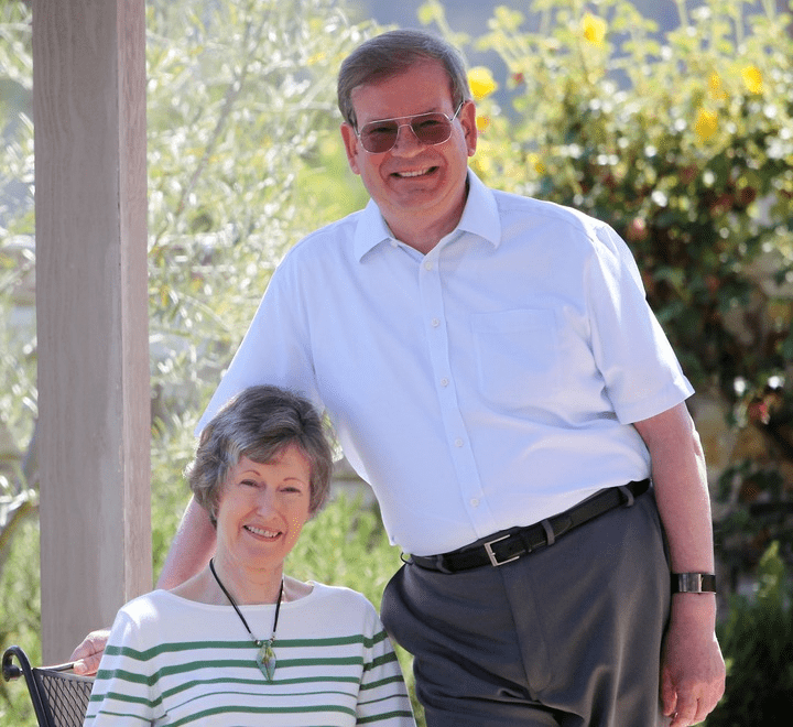 Graham Siddall standing next to his wife Brenda who is sitting in a chair