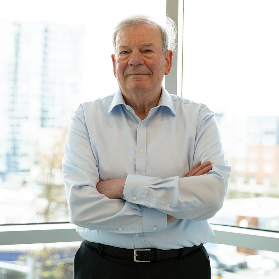 Portrait of Graham Siddall smiling, standing with his arms crossed
