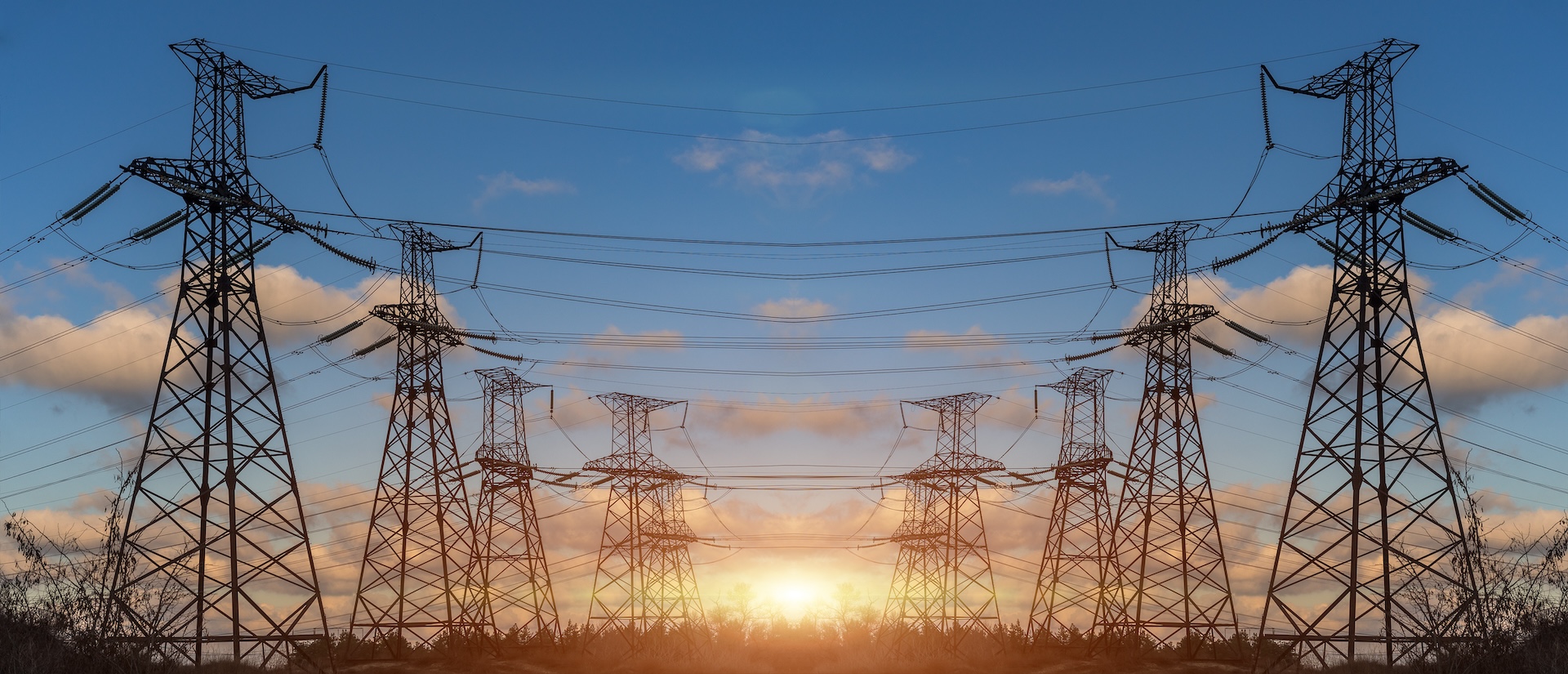 High Voltage Electric Transmission Tower Energy Pylon with a setting sun in the background