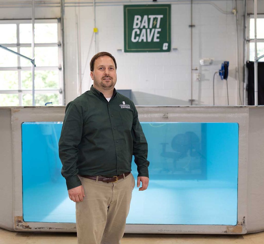 Artur Wolek stands in front of a water tank in the BATT CAVE research center